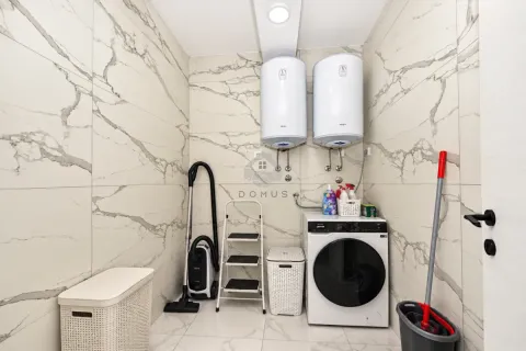 Bathroom equipped with a washing machine, water heaters, and cleaning supplies. - image 17
