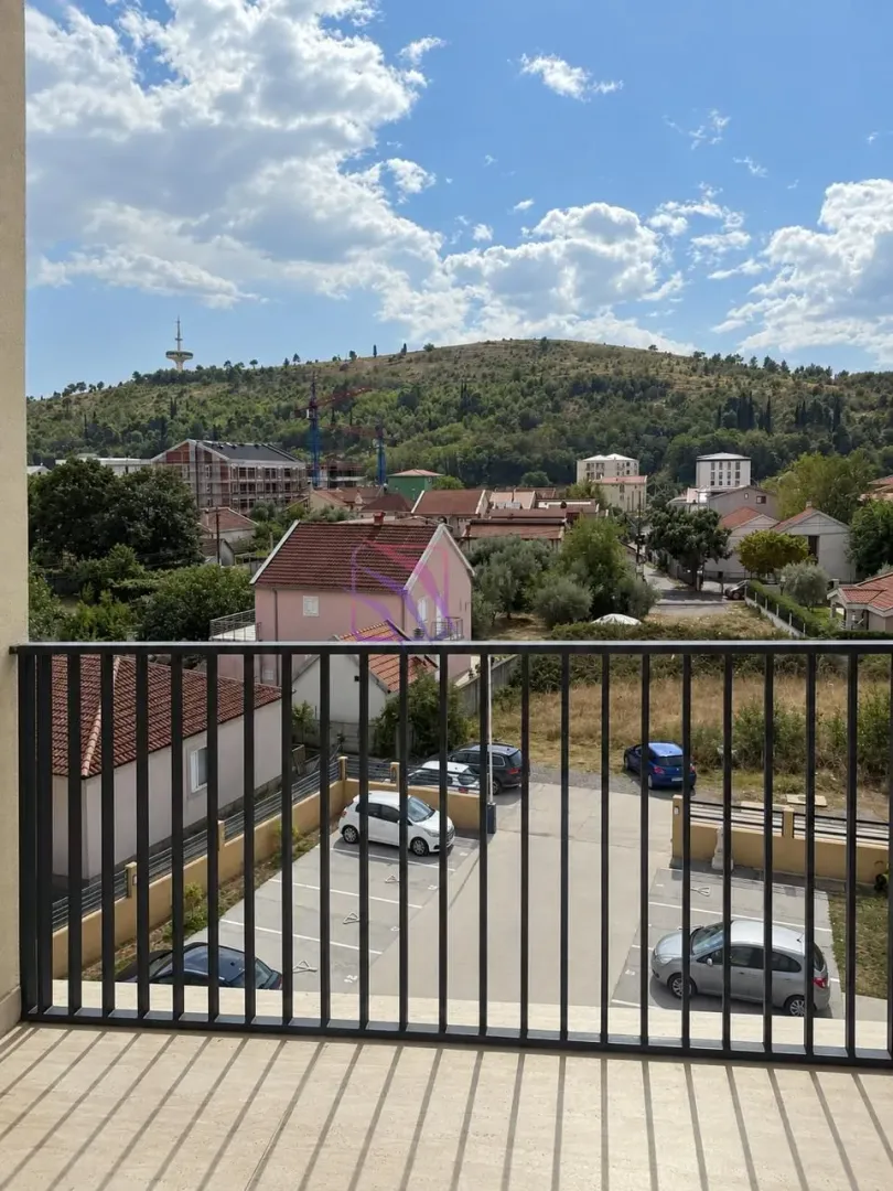 Pogled sa balkona na okolno naselje i brdo.