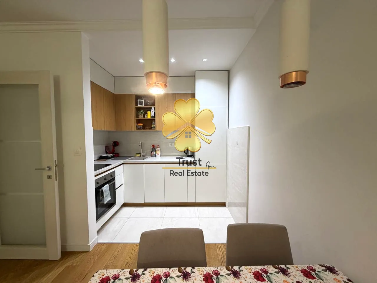 Modern kitchen with white cabinets and a dining table in the foreground.