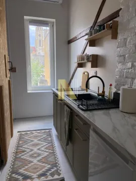 Manja kuhinja sa sudoperom, radnom površinom i prozorom koji gleda na grad. - image 6