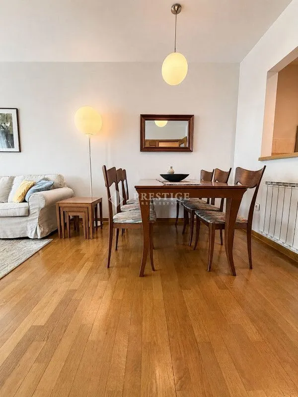 Living room with dining area, parquet flooring and a sofa.