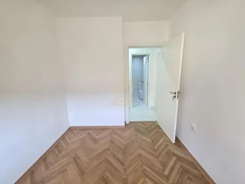 Prazna soba sa belim zidovima i drvenim podom. - image 4