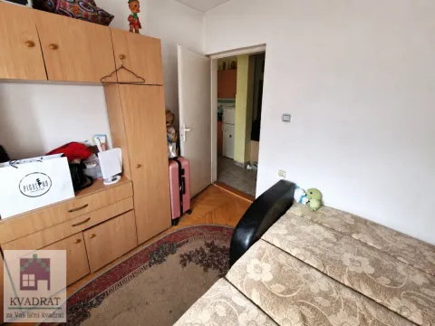 Small bedroom with a bed, wooden wardrobe, and carpet. - image 7