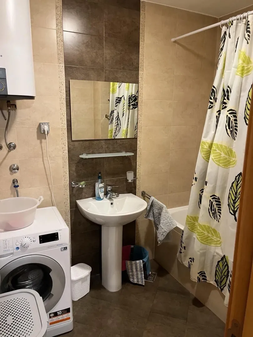 A bathroom with a bathtub, a pedestal sink, and a washing machine.