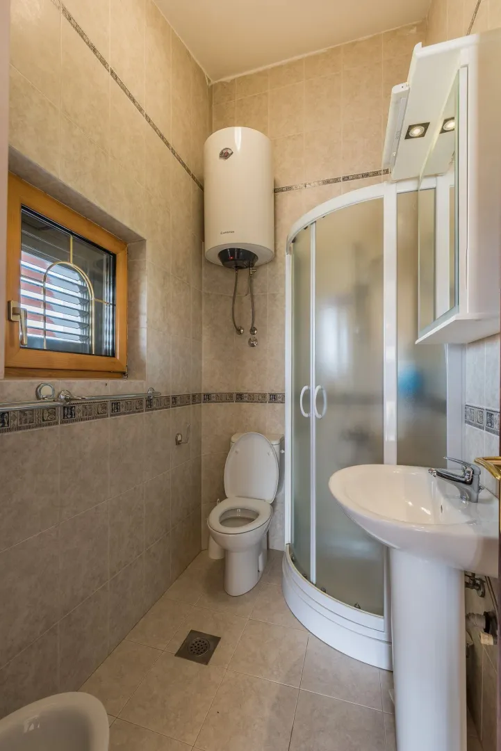 Bright bathroom with a shower cabin and water heater.