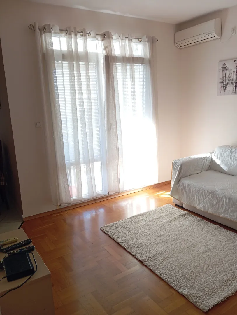 Dnevna soba sa garniturom, parketom i izlazom na terasu.