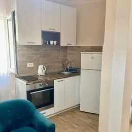 Small kitchen with white cabinetry, built-in oven, and refrigerator. - image 2