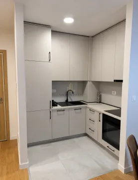 Modern corner kitchen with light cabinets and built-in oven. - image 2
