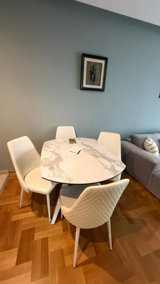 Dining table with white chairs in the living room.
