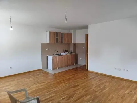 Living room with a small kitchen area and wooden flooring. - image 5