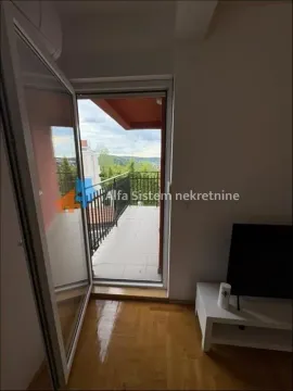 Pogled iz dnevne sobe na terasu sa metalnom ogradom i zelenilom u pozadini. - image 12