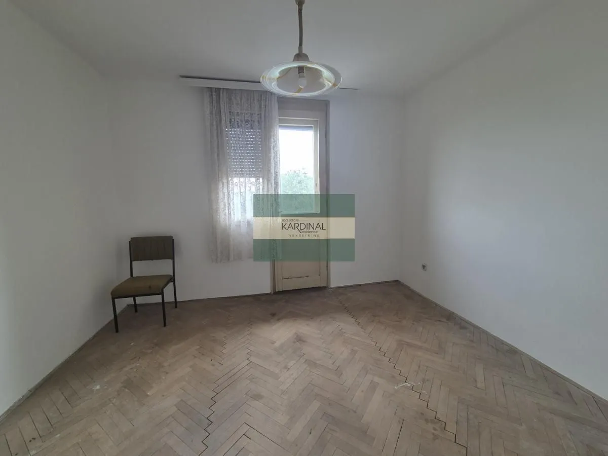 Prazna soba sa parketom na podu i jednom stolicom.