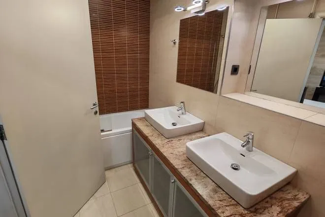 Bathroom with two washbasins, a countertop, and a bathtub.