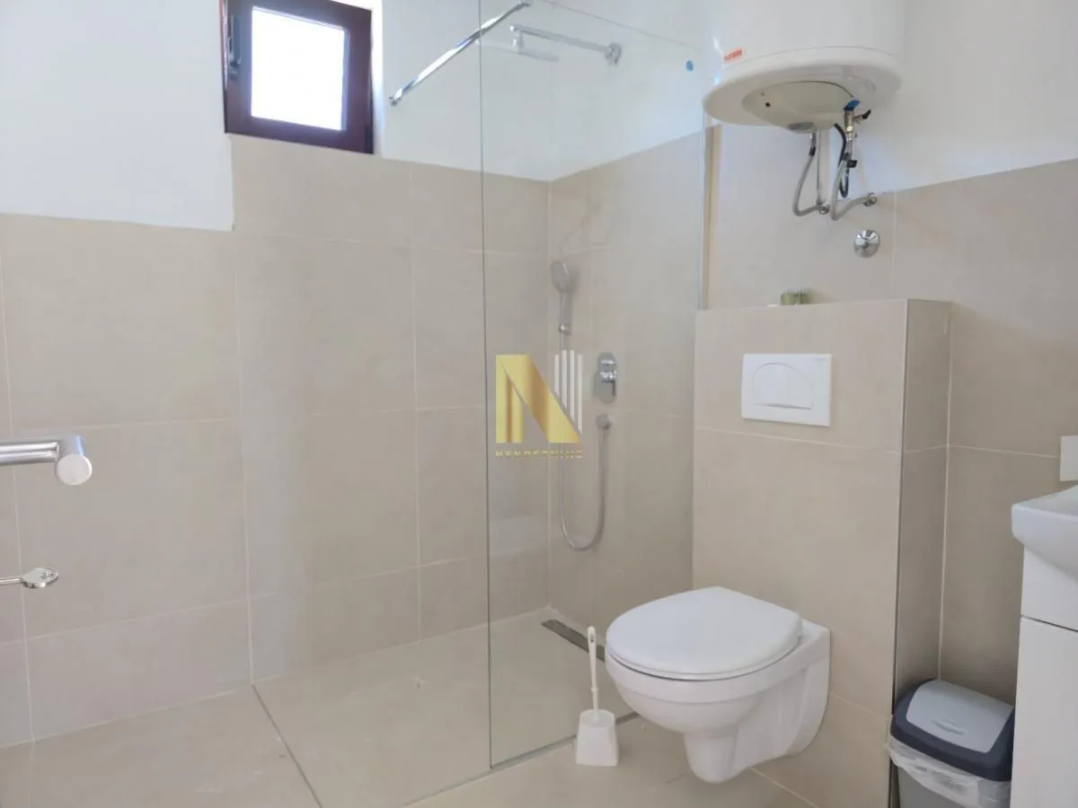 Moderno opremljeno kupatilo sa tuš kabinom i sanitarijama.