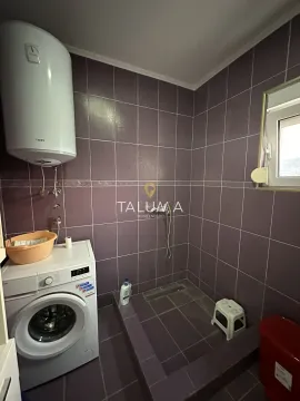 Bathroom lined with purple tiles featuring a walk-in shower, water heater, and washing machine. - image 2