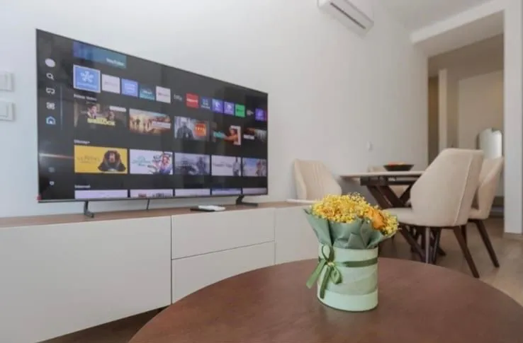 Living room with a TV and a dining table in the background.