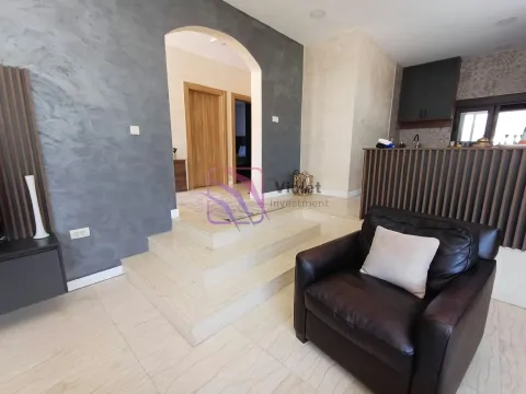 Living room with an armchair, steps, and a view towards the kitchen and hallway. - image 8