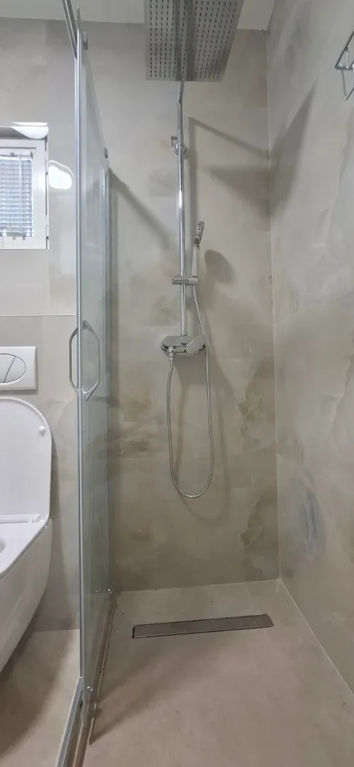 Moderne kupatilo sa tuš kabinom i ugradnim elementima.