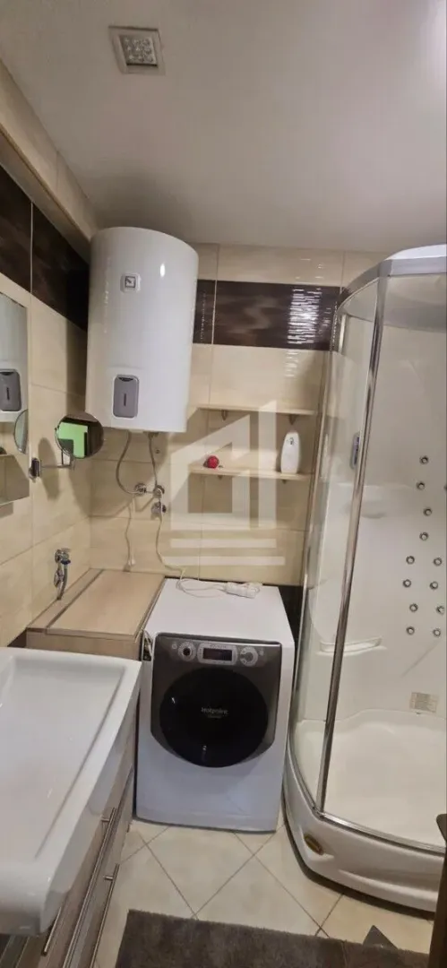 Bathroom equipped with a shower cabin, washbasin, washing machine, and water heater.