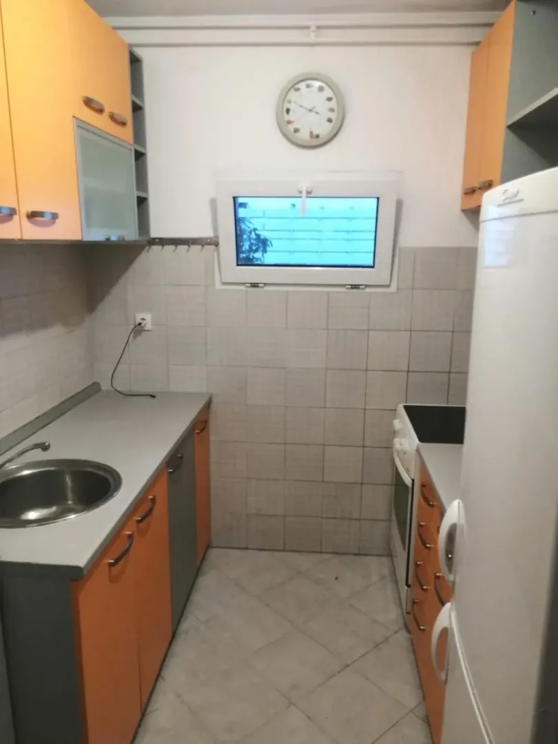 Small kitchen with orange cabinets and a sink.