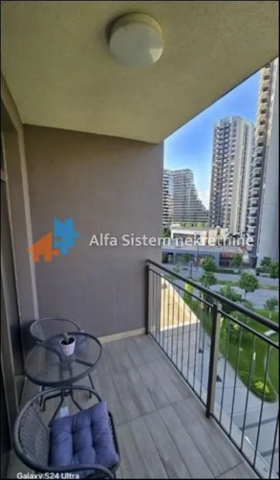 Natkriveni balkon sa garniturom za sedenje i pogledom na naselje.