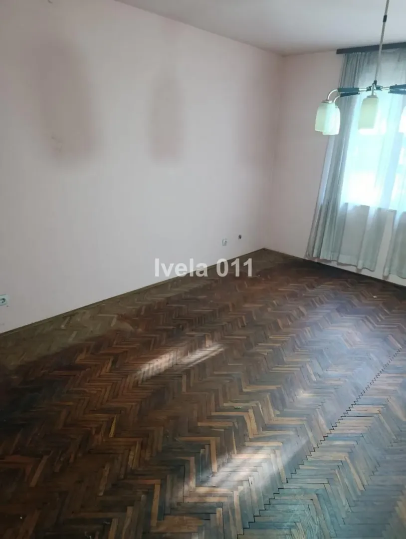 Prazna prostorija sa parketom i prozorom.