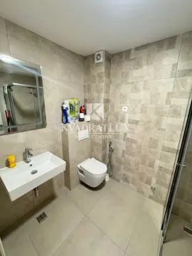 Moderne kupatilo obloženo keramičkim pločicama sa umivaonikom i toaletom. - image 3