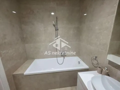 Bathroom equipped with a bathtub, washbasin, and beige ceramic tiles. - image 21