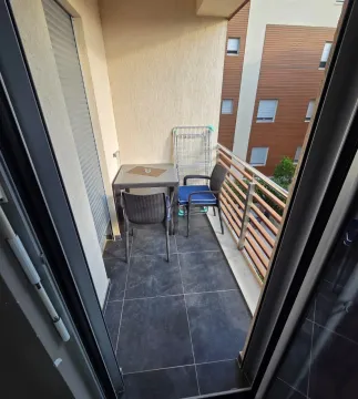 Small furnished balcony with a table, chairs, and a drying rack. - image 8