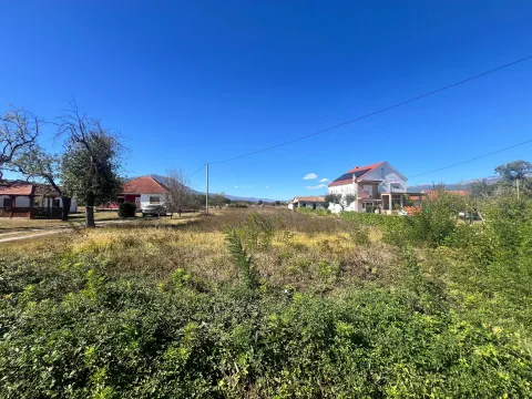 Pogled na plac sa travnatom površinom i kućama u pozadini. - image 2