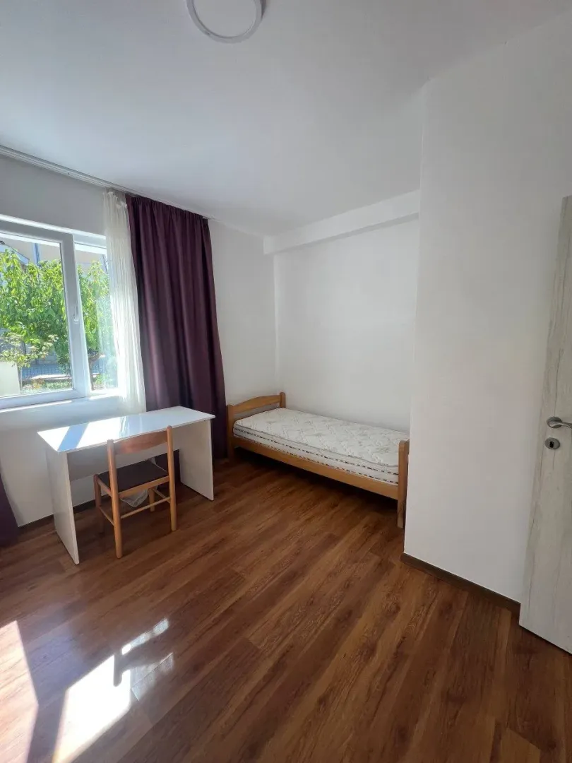 Small bedroom with a bed, desk, and window.