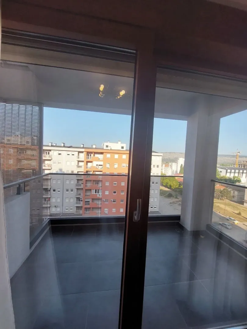 Pogled sa balkona na okolne zgrade i gradski krajolik.