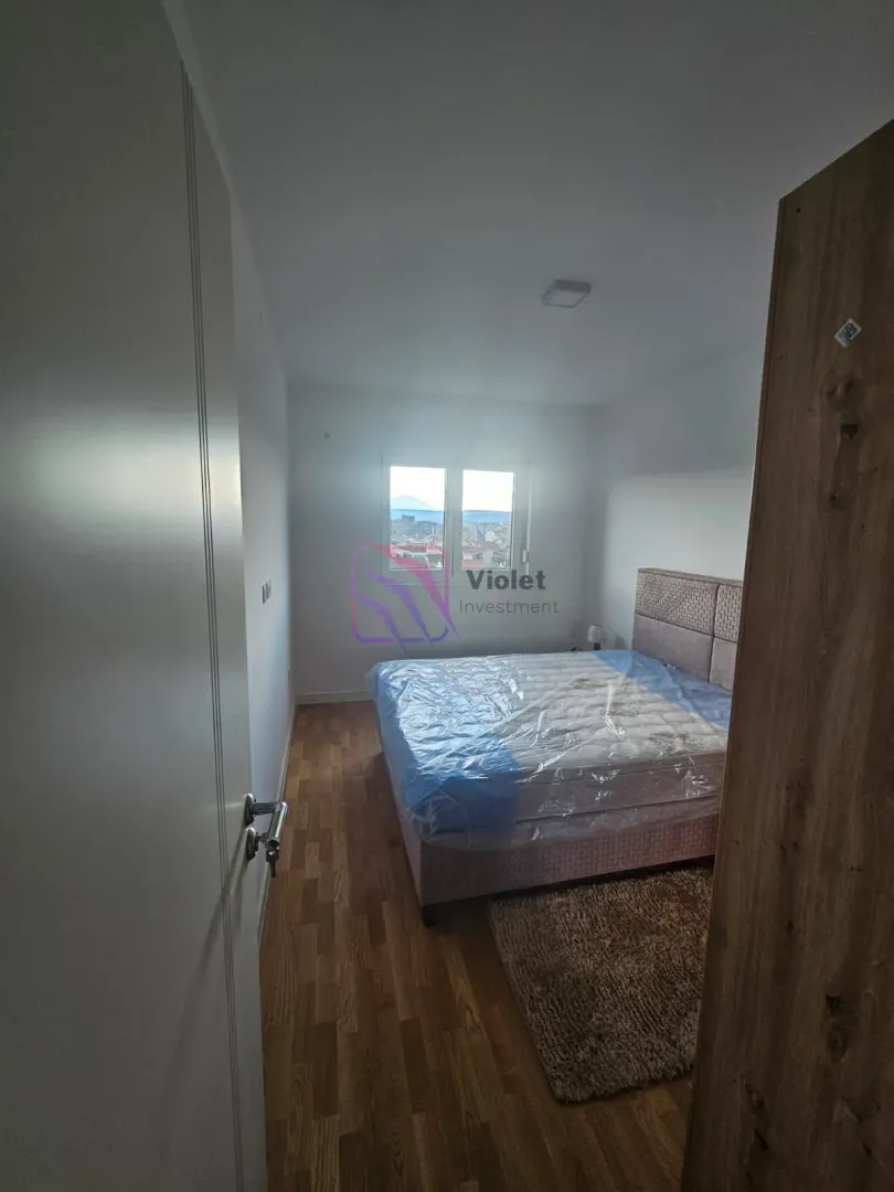 Namještena spavaća soba sa krevetom i prozorom koji gleda na grad.