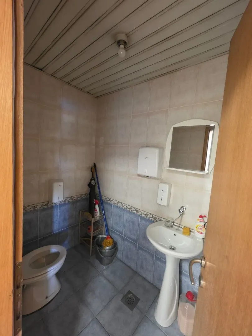 Small bathroom with a sink, toilet and cleaning supplies.