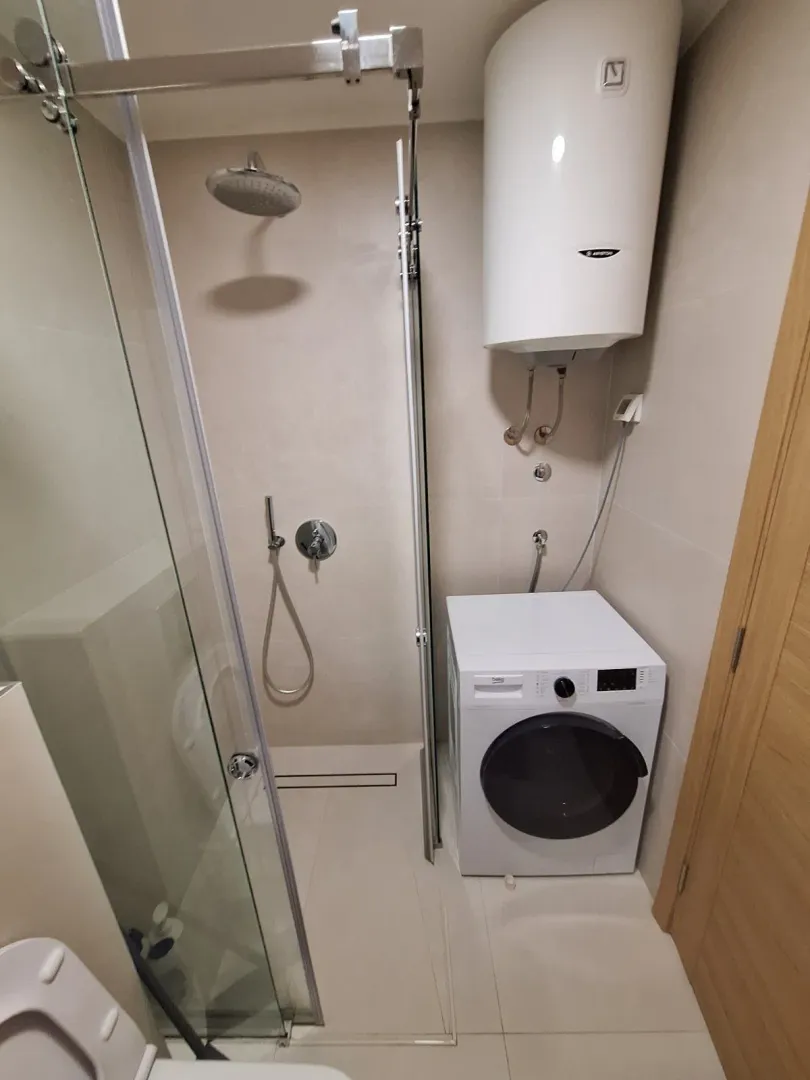 Bathroom with a walk-in shower, water heater, and washing machine.
