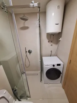 Bathroom with a walk-in shower, water heater, and washing machine. - image 9