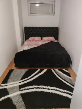 A small bedroom featuring a double bed with a black headboard and a patterned rug. - image 21