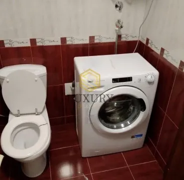 Manje kupatilo sa toaletom i veš mašinom obloženo tamnim pločicama. - image 3