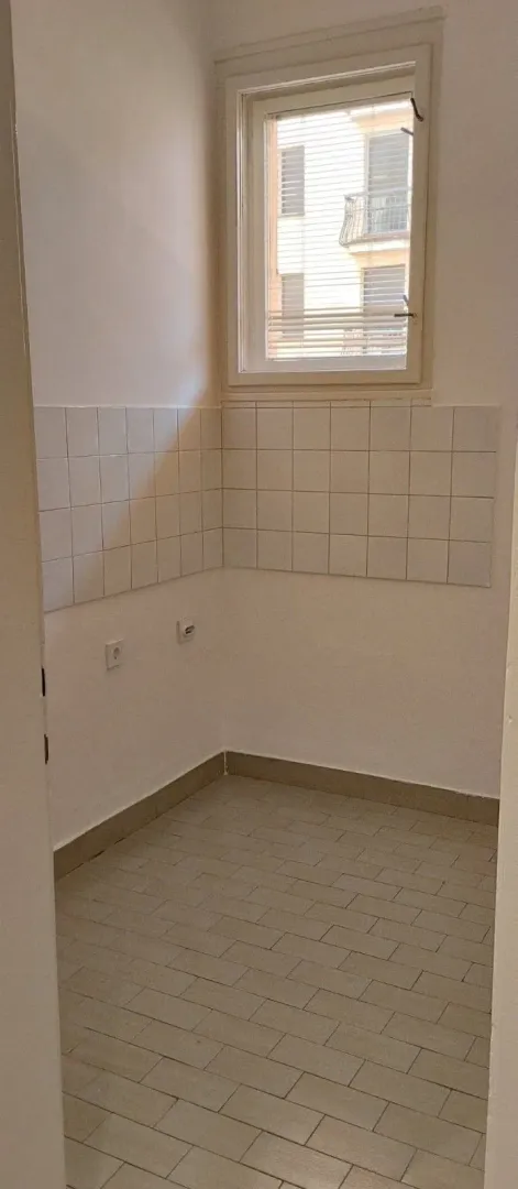 Prazan dio prostorije sa pločicama na zidu i prozorom.