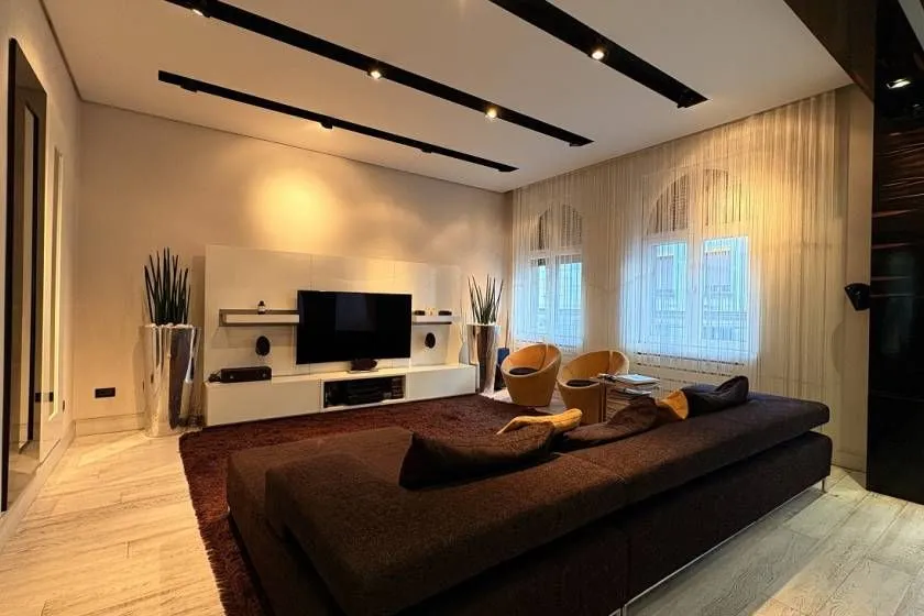 Modern living room with a sofa, TV, and recessed lighting.