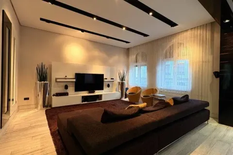 Modern living room with a sofa, TV, and recessed lighting. - image 2