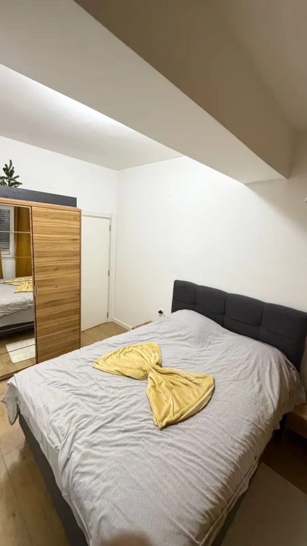 Spavaća soba sa bračnim krevetom, garderoberom sa ogledalom i bijelim zidovima.