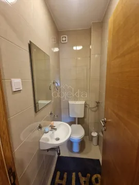 Small bathroom with a sink, mirror, and toilet tiled with ceramic tiles. - image 9