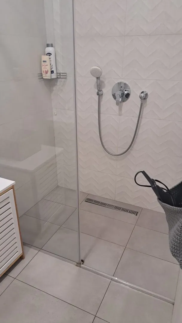 Moderna tuš-kabina sa staklenom pregradom u svijetlom kupatilu.