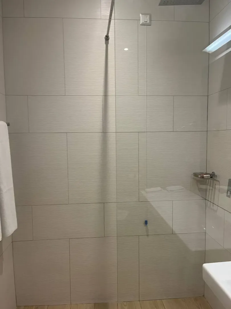 Modern bathroom with a glass shower enclosure and light tiles.
