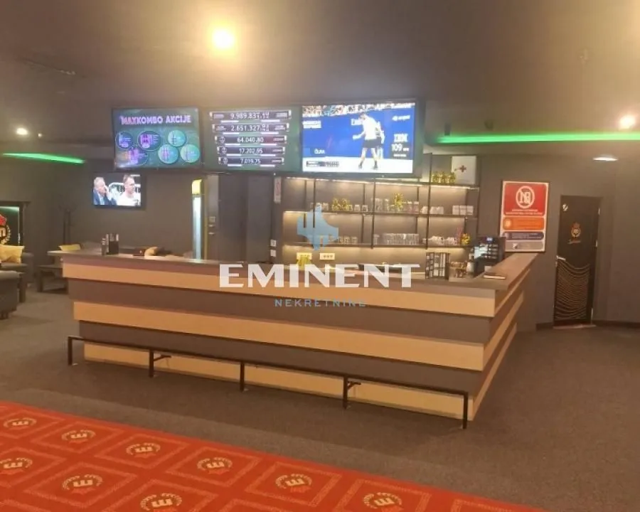 Interior of a commercial space with a bar counter and screens on the wall.