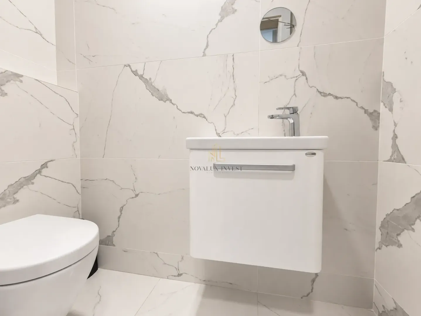 Modernly equipped bathroom with a washbasin and white marble-effect ceramic tiles.