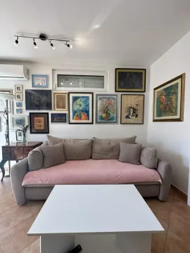 Dnevna soba sa garniturom, stočićem i zidom ukrašenim slikama. - image 5