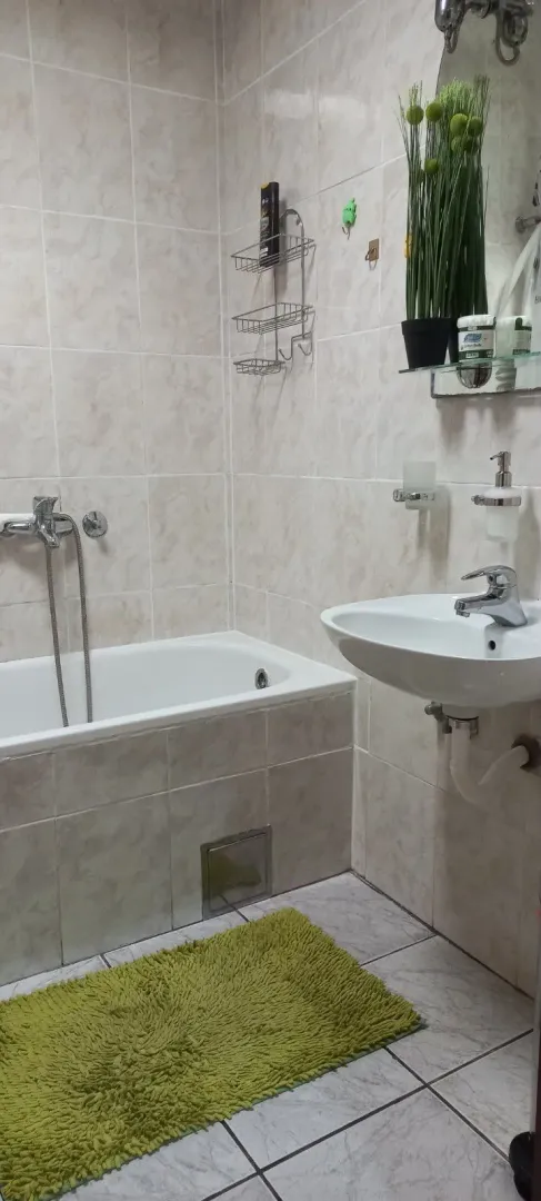 Small bathroom with a bathtub, washbasin, and neutral-toned tiles.