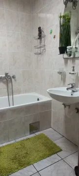 Small bathroom with a bathtub, washbasin, and neutral-toned tiles. - image 6